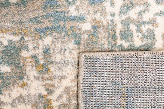 Large area rug corner detail with distressed mosaic pattern and stitched border; cream and blue