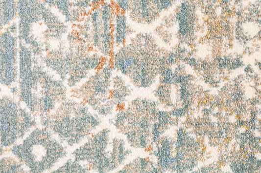 Large area rug close-up showing faded abstract motifs in light blue, cream, and speckled tan.