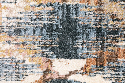 Modern area rug close-up with dark blue, tan, and cream abstract blocks