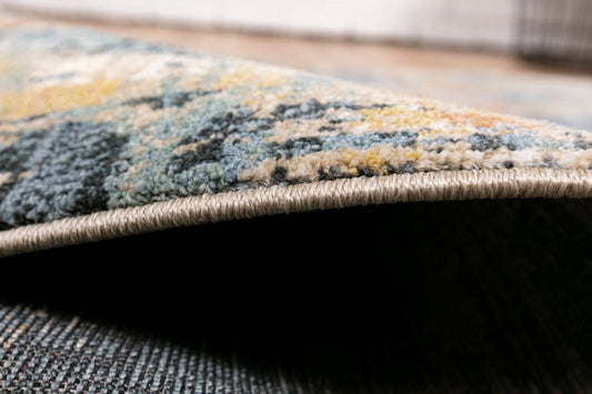 Modern area rug edge with textured pile and layered blue and taupe pattern
