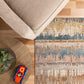Beige area rug with blue and tan abstract pattern under beige sofa