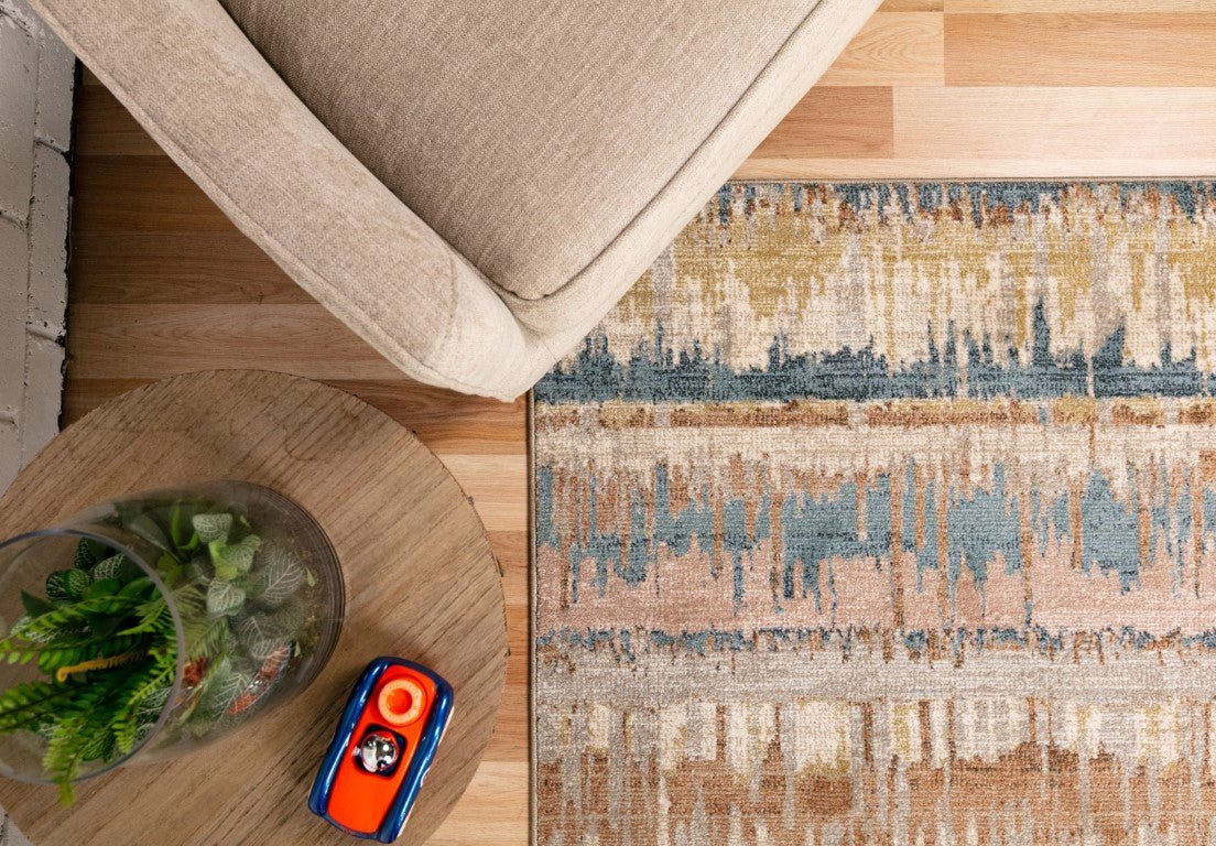 Beige area rug with blue and tan abstract pattern under beige sofa