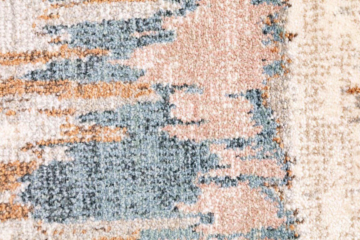 Beige area rug close-up with blue and rust abstract design texture