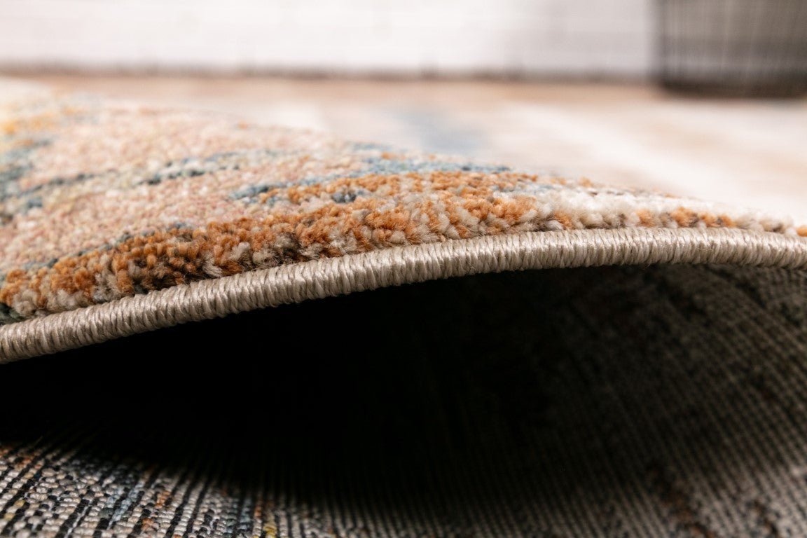 Beige area rug edge detail with tightly looped pile and stitched border