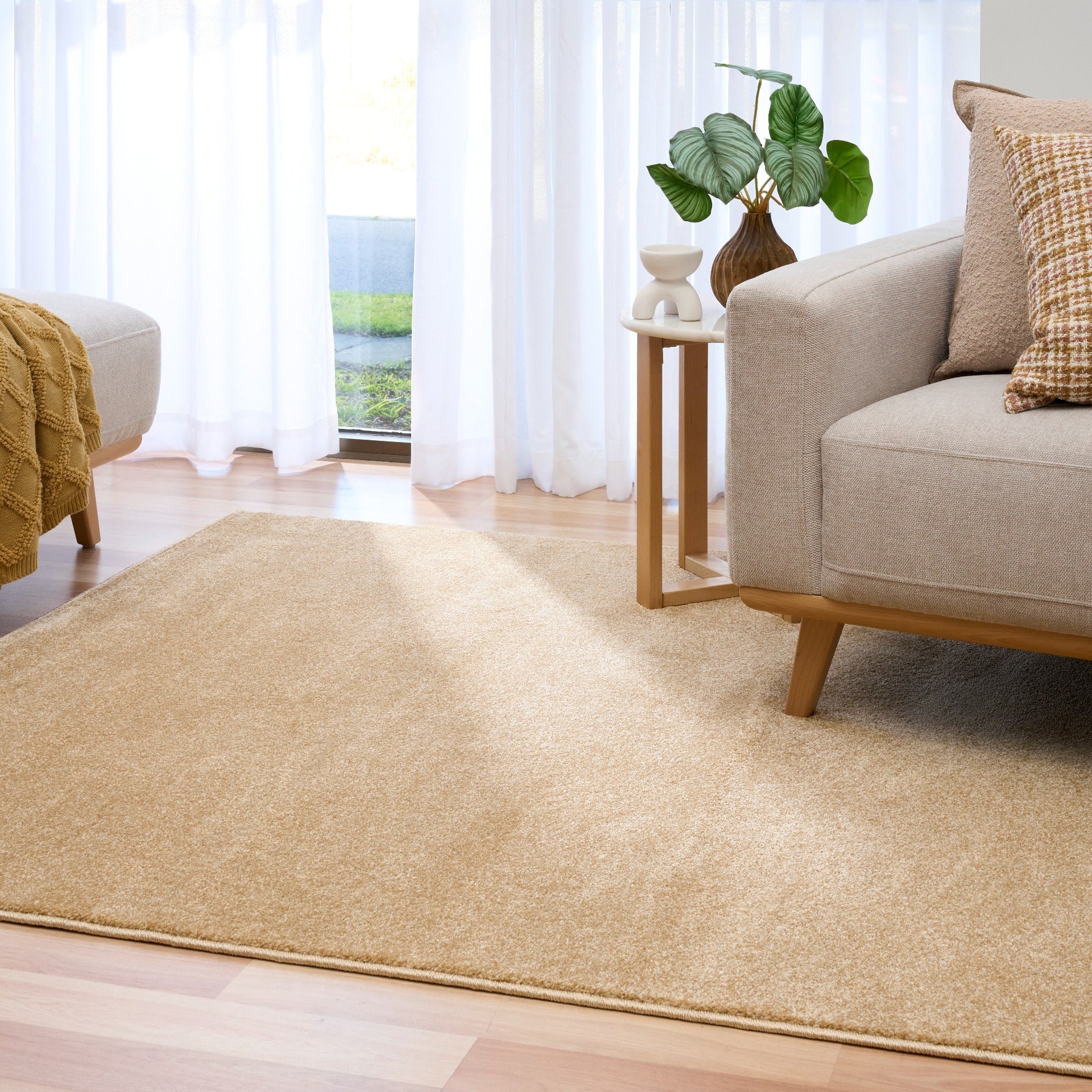 Beige area rug covering wood floor beside beige sofa | Eclipse Nimes Modern Abstract Living Room Rug - Rugs Point Australia