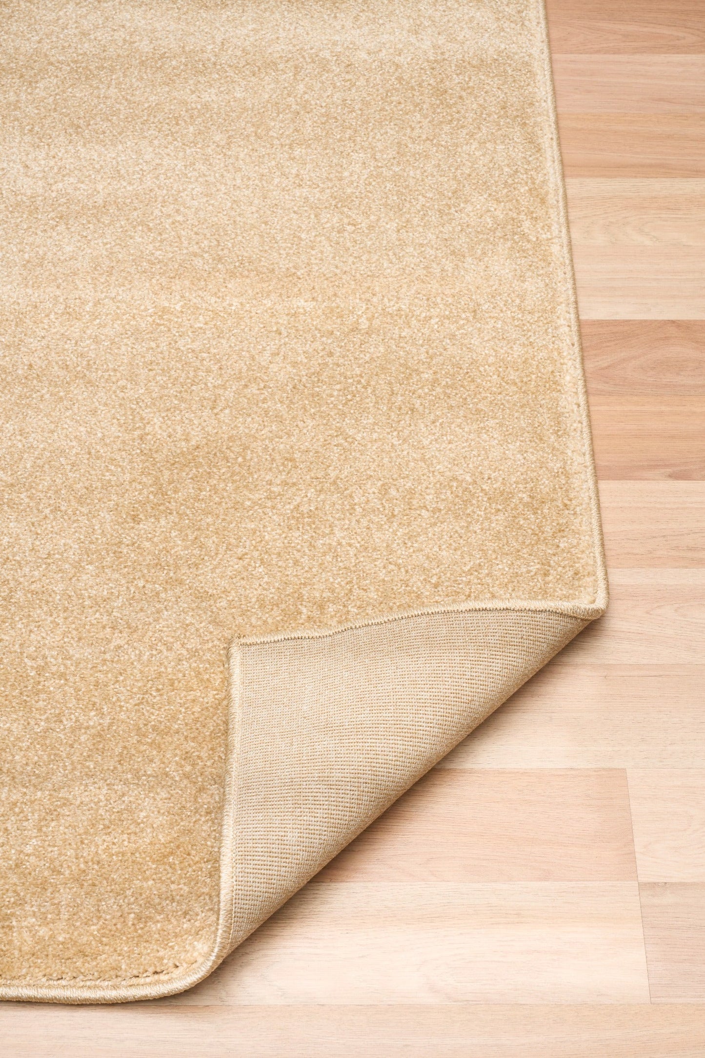 Beige area rug corner showing folded backing on light wood floor | Eclipse Nimes Modern Abstract Living Room Rug - Rugs Point Australia