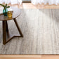 Dark grey wool rug spread across floor near seating area, showing striped texture