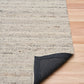 Smoke grey wool rug with visible corner edge and speckled woven texture