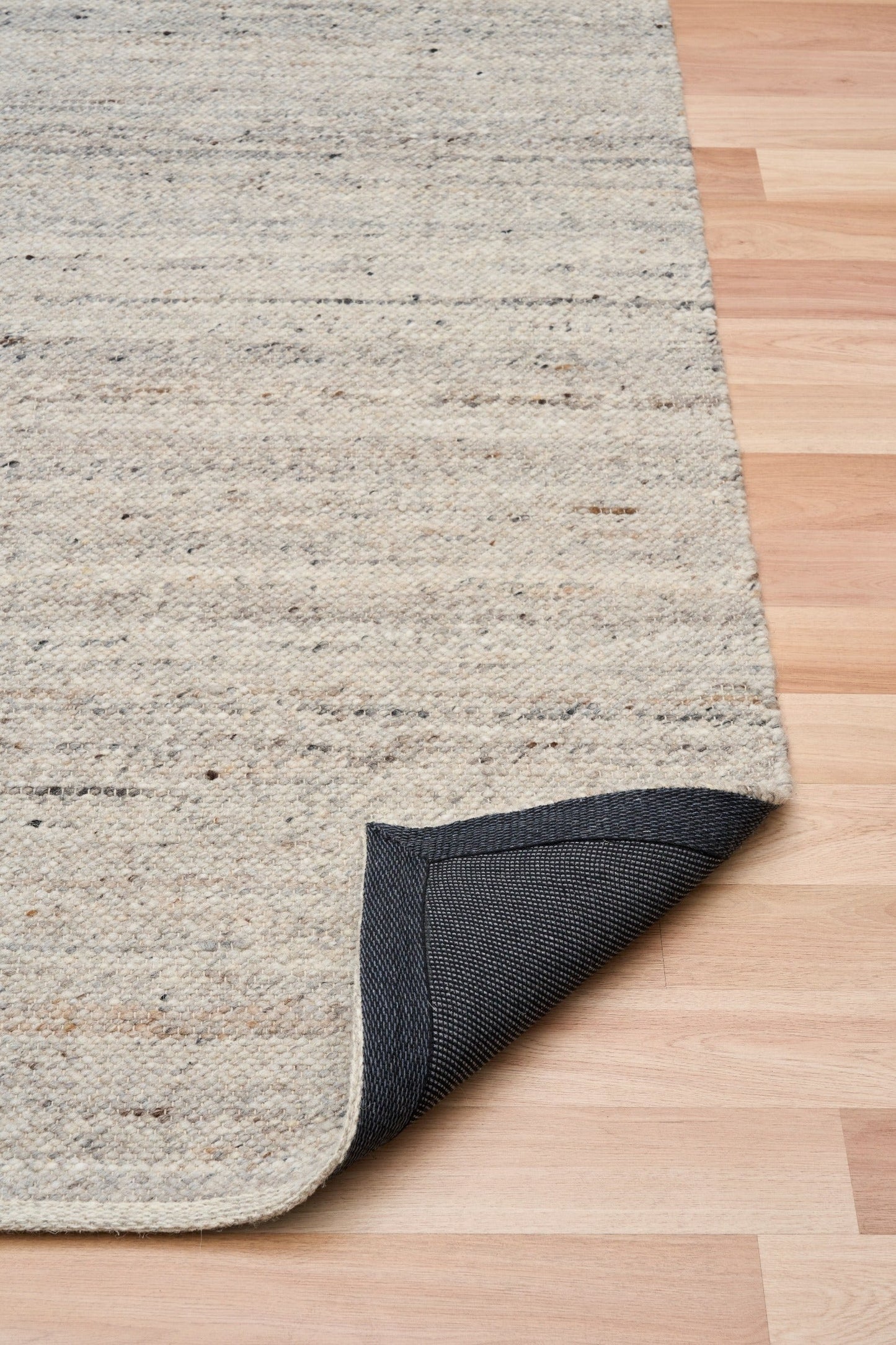 Smoke grey wool rug with visible corner edge and speckled woven texture
