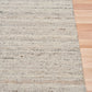 Smoke grey wool rug edge detail with speckled horizontal texture and binding