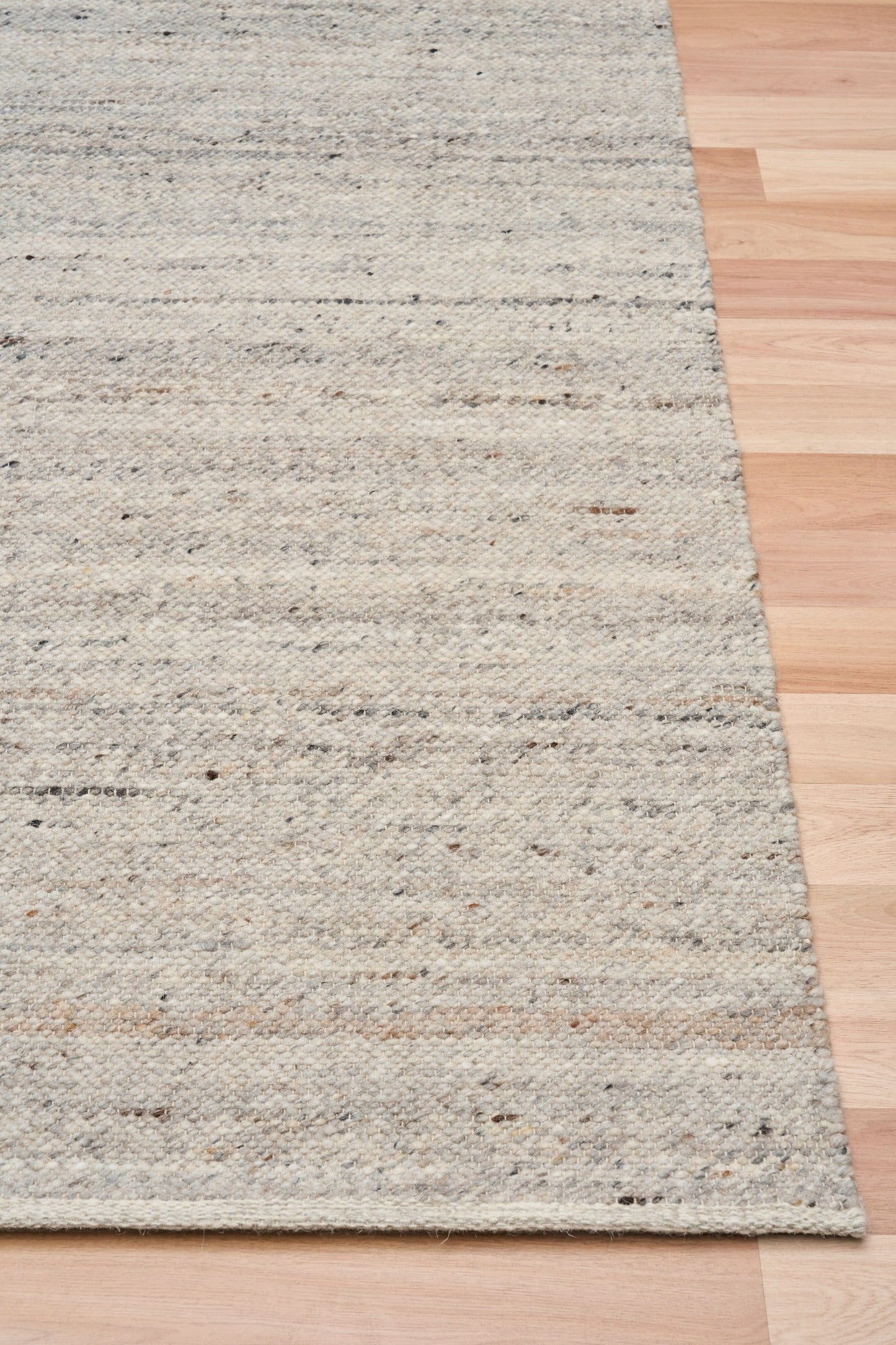 Smoke grey wool rug edge detail with speckled horizontal texture and binding