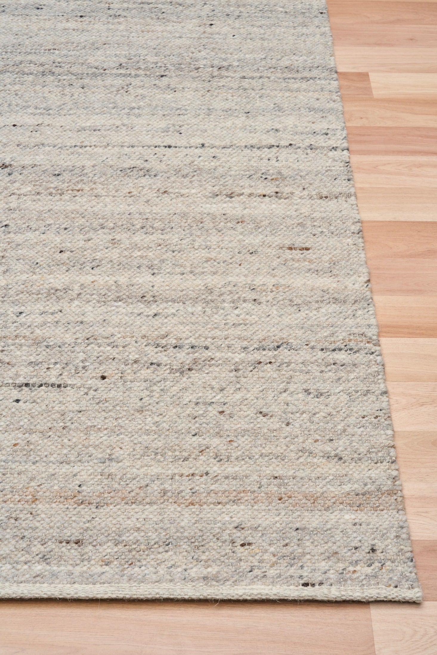 Smoke grey wool rug edge detail with speckled horizontal texture and binding