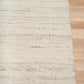 White wool rug corner with textured surface and clean overlocked edge