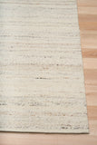 White wool rug corner with textured surface and clean overlocked edge