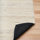 White wool rug with dark bound backing along the corner edge