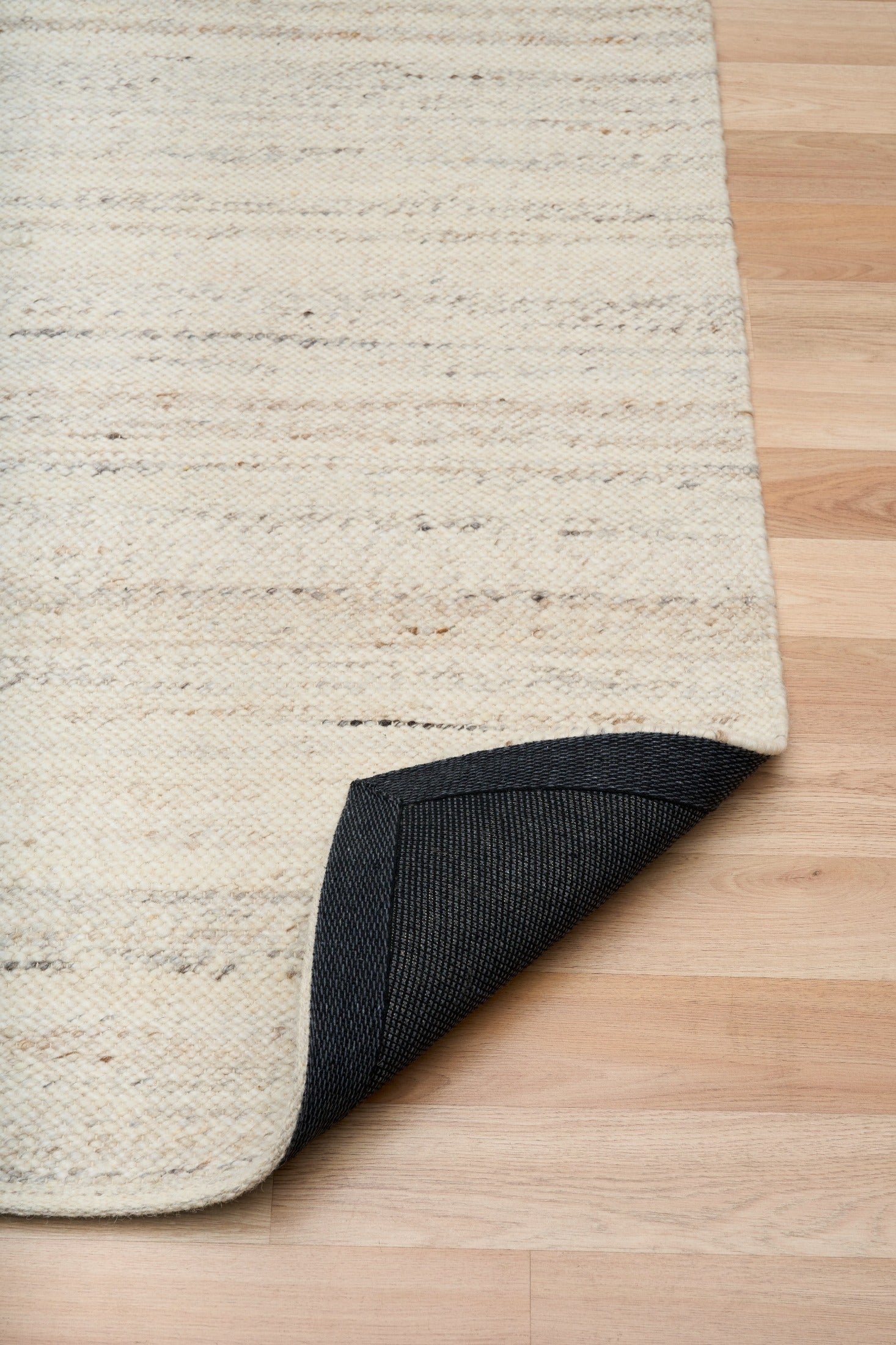 White wool rug with dark bound backing along the corner edge