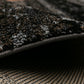 Black area rug edge with stitched binding and textured low-pile surface