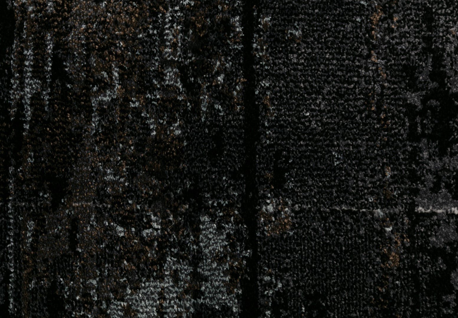 Black area rug close-up with grainy mottled gray speckles