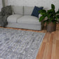 Grey distressed abstract area rug with border, shown laid on hardwood floor