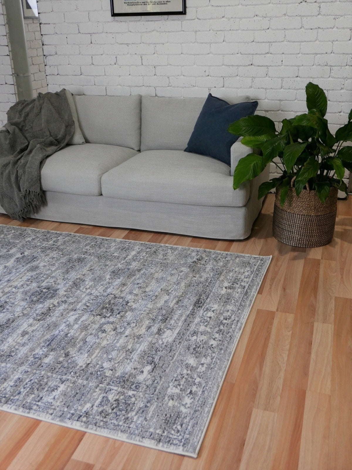 Grey distressed abstract area rug with border, shown laid on hardwood floor