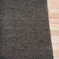 Charcoal textured area rug corner with stitched border