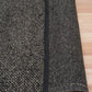 Charcoal textured area rug corner detail with thick edge binding