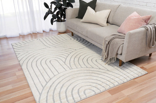 Ivory and light gray shagg rug with arched stripe pattern on wood floor
