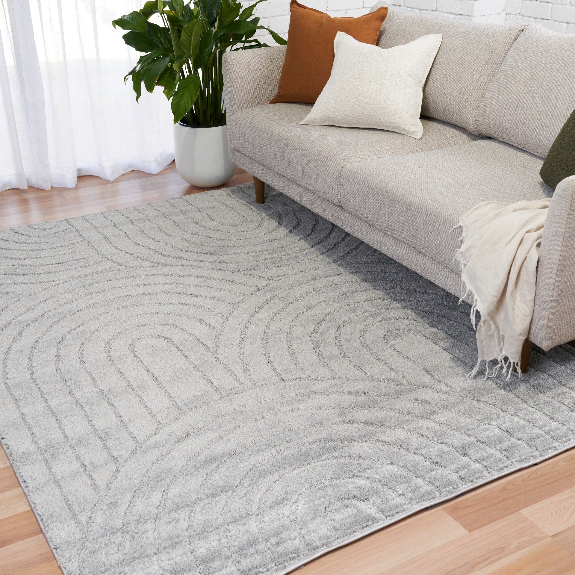 Light grey shag rug with wave and circular stitched design, visible corner