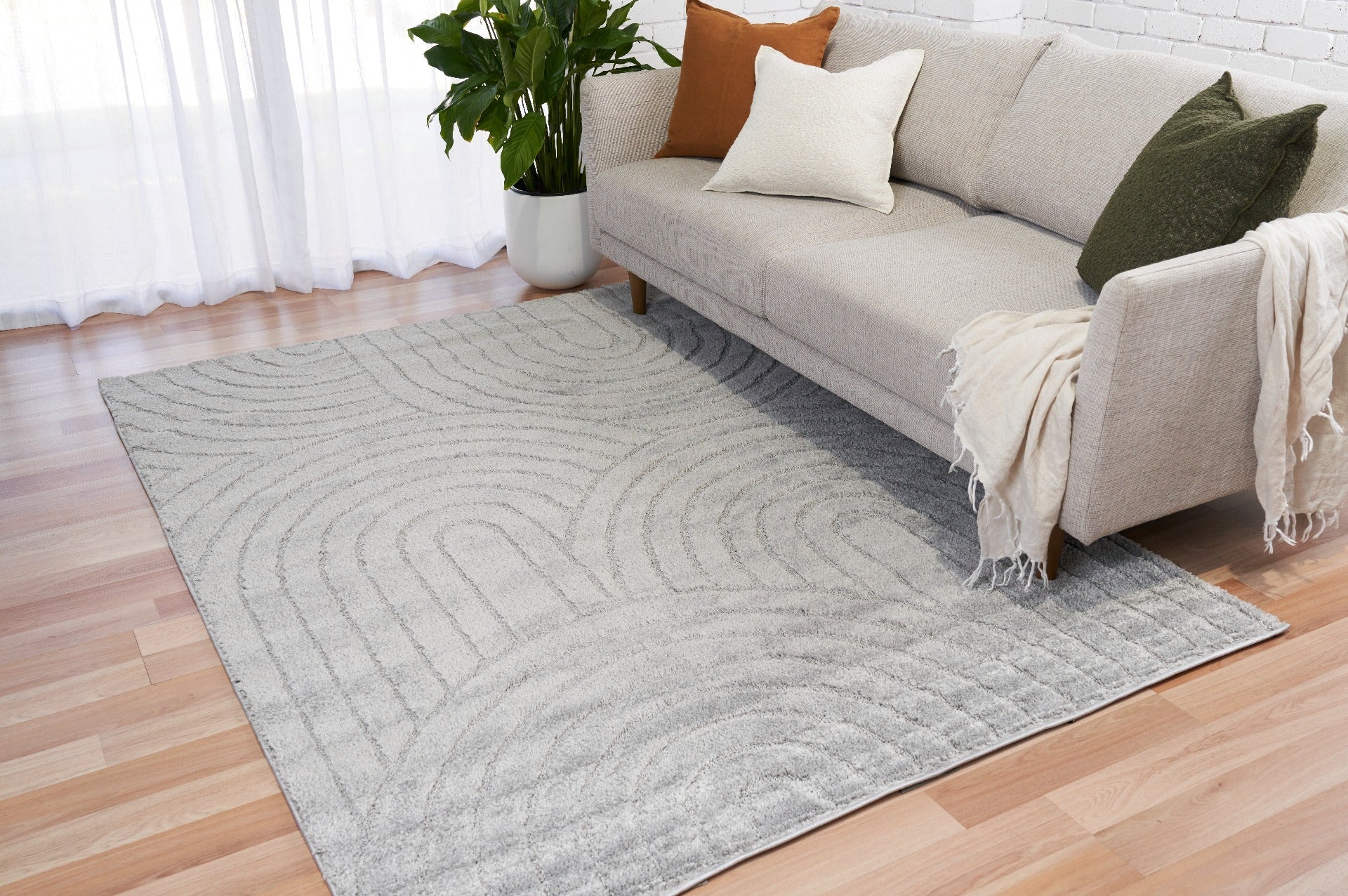 Light grey shag rug with wave and circular stitched motif on hardwood floor