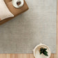 Light gray woven rug with corner visible and close, speckled texture