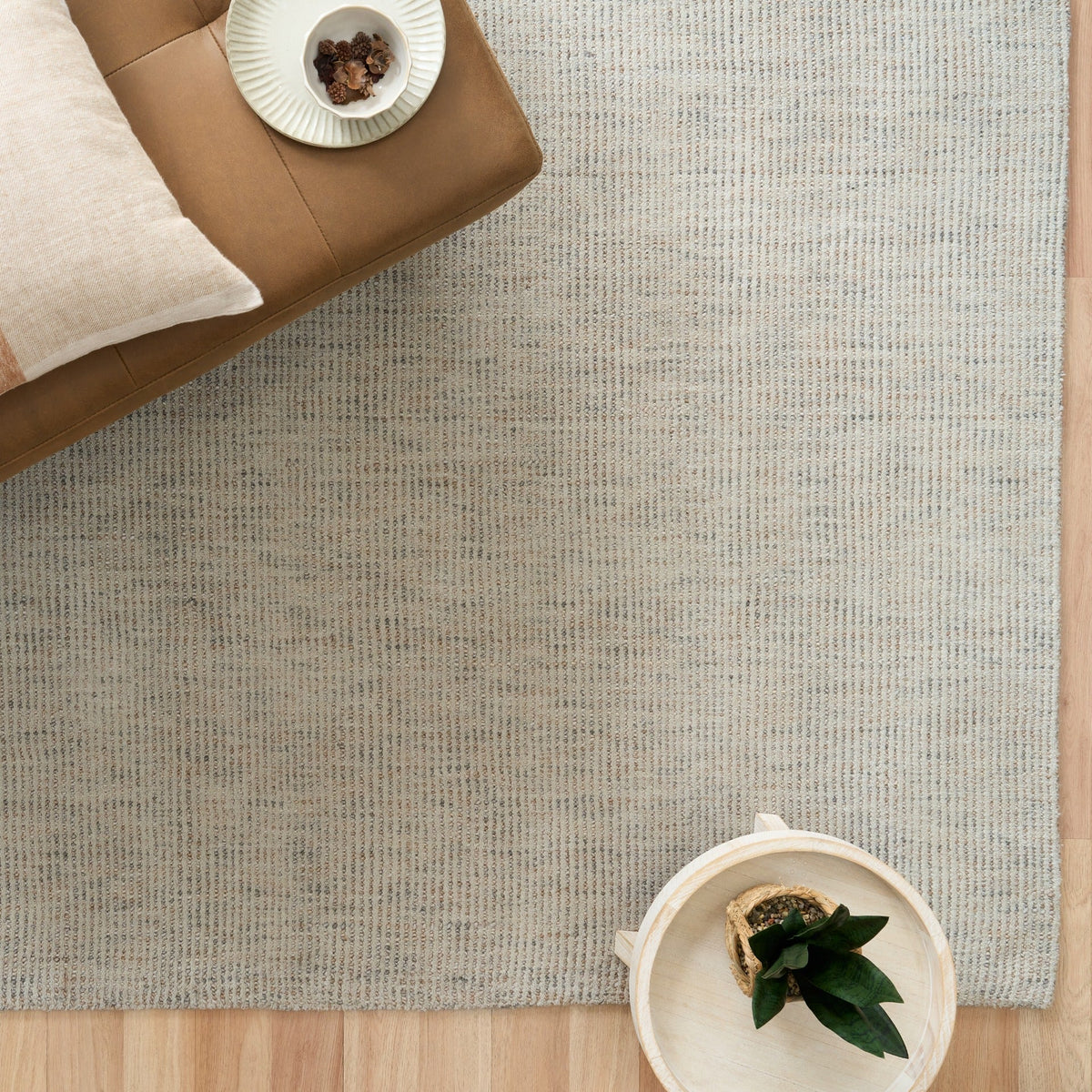 Light gray woven rug with corner visible and close, speckled texture