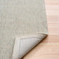 Light gray woven area rug with bound edge corner detail