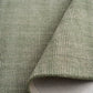 Green area rug fabric close-up with curled edge and light interior backing