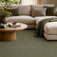 Green area rug under a modern sectional sofa with pillows and a draped throw