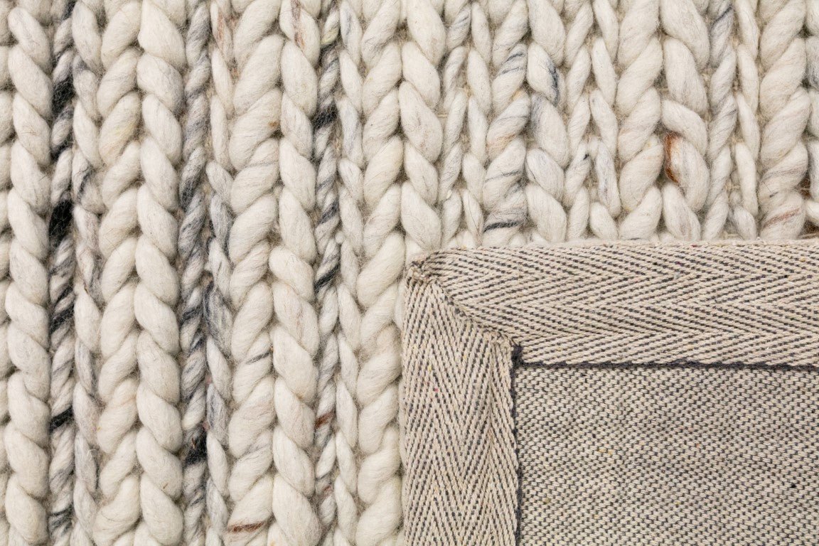 Ivory chunky knit wool rug corner with stitched border detail