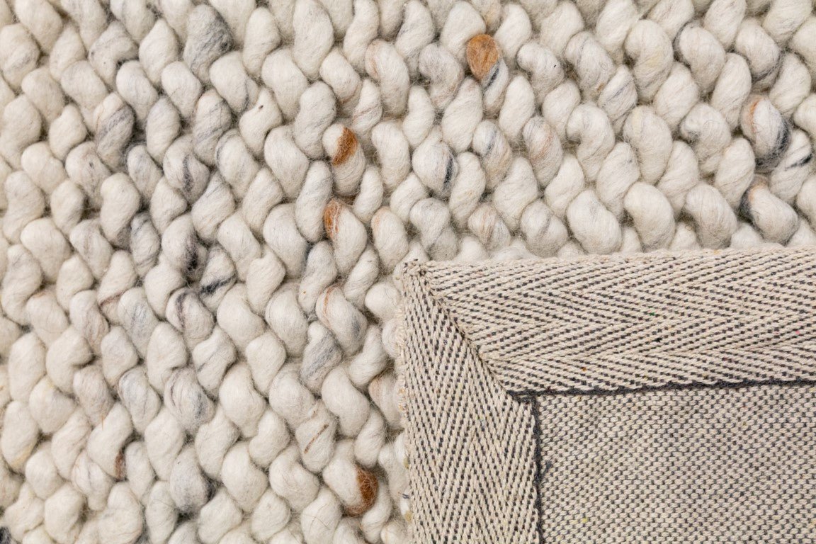Wool rug corner with thick loop pile and tightly stitched border edge