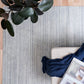Blue-gray wool floor rug with vertical textured stripes and folded edge