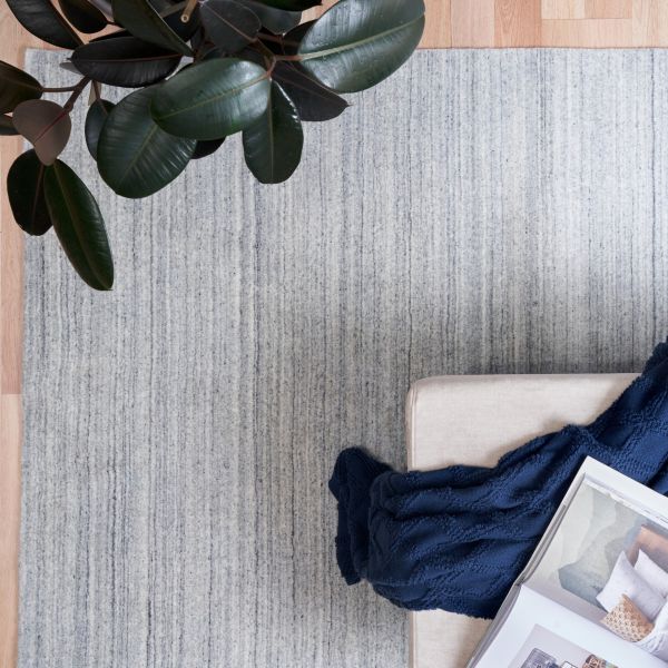Blue-gray wool floor rug with vertical textured stripes and folded edge