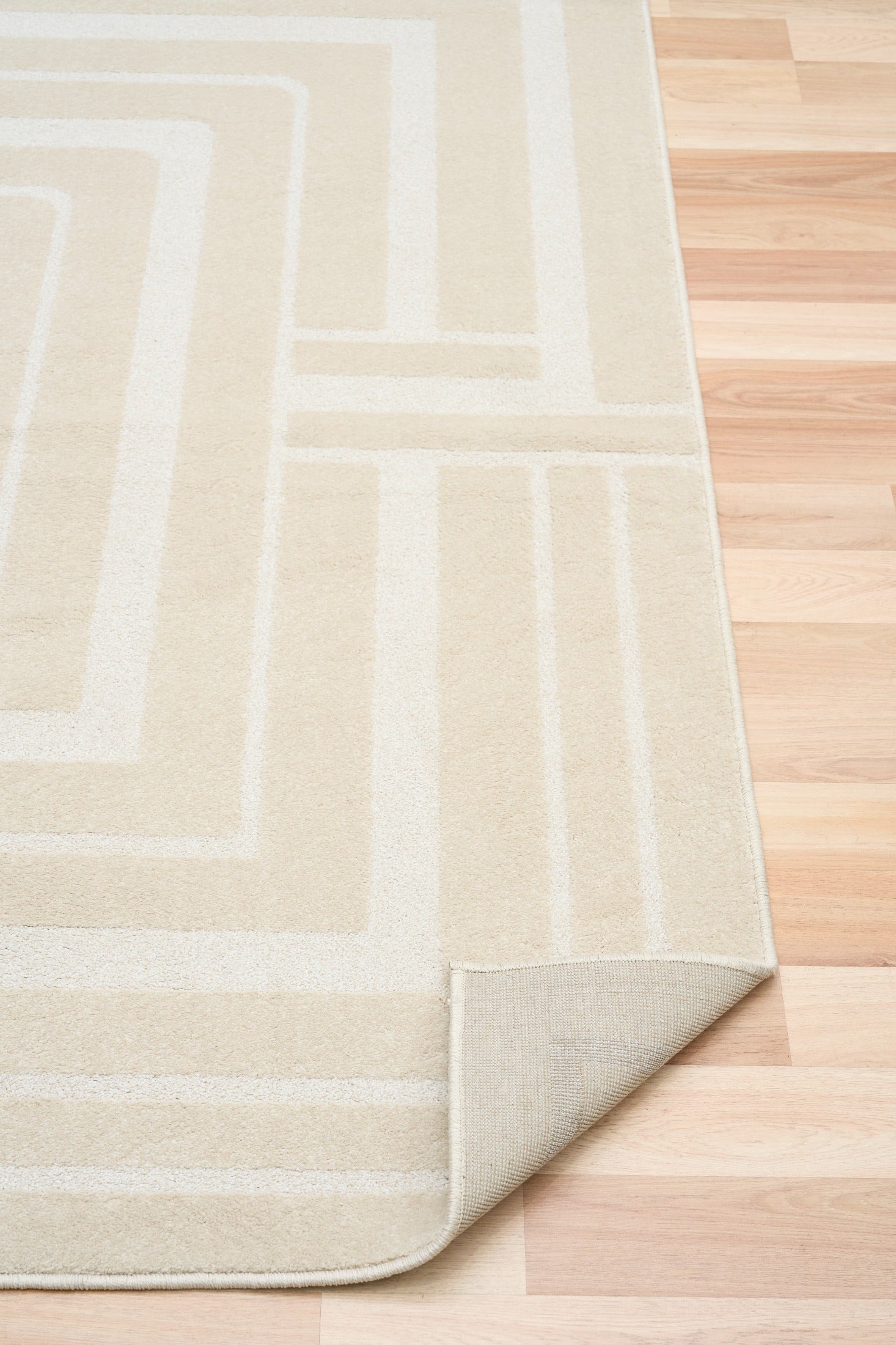 Ozlo ecru patterned area rug corner with stitched edge