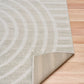 Light gray area rug with abstract arch and stripe motif, angled view of edge