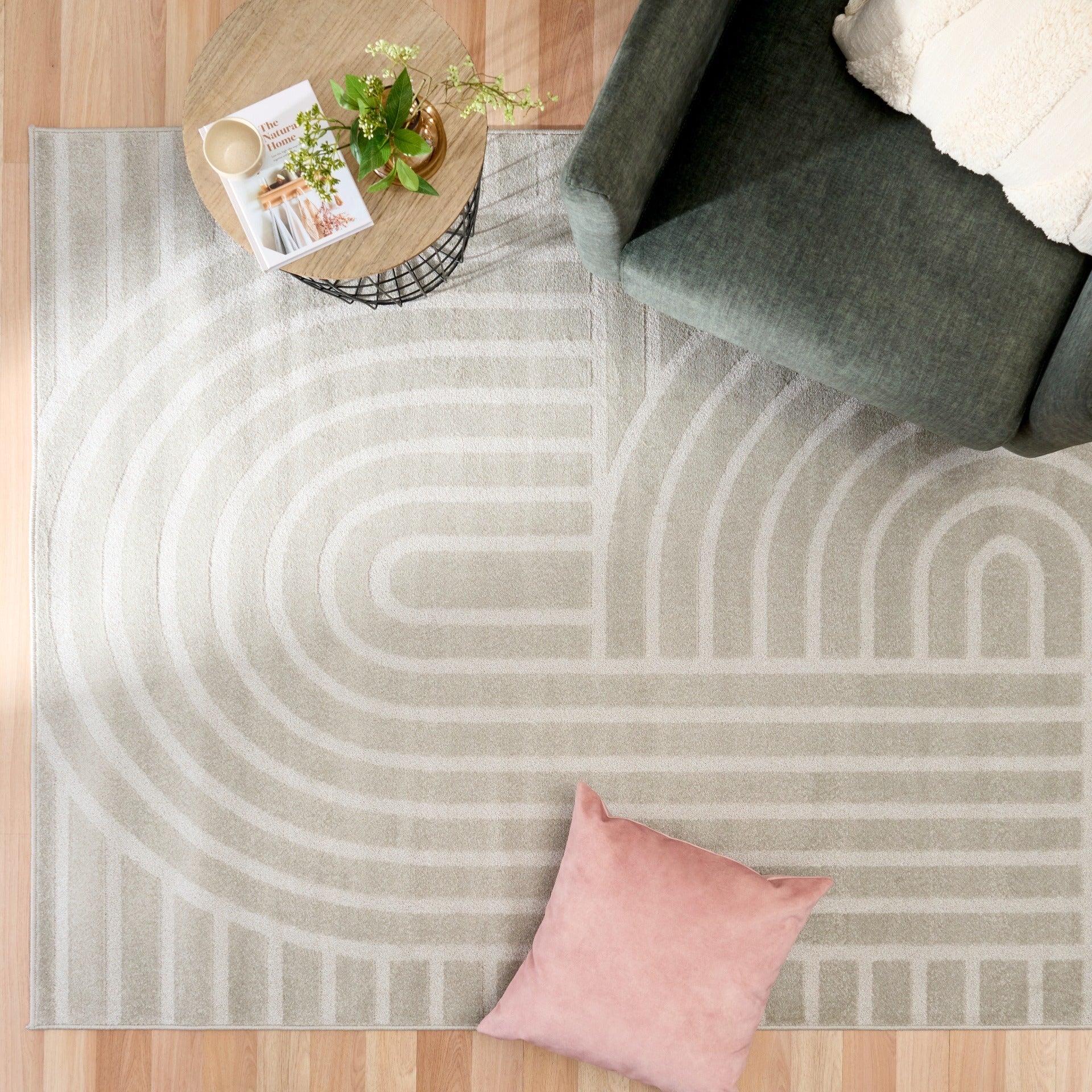 Light gray area rug with abstract arch and bar stripe pattern, styled with pillows