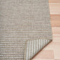Folded edge of woven outdoor rug with striped border and textured weave