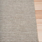 Woven outdoor rug corner with striped texture and flat border detail