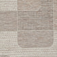 Woven rug surface with beige and taupe patchwork blocks and stitched stripe lines