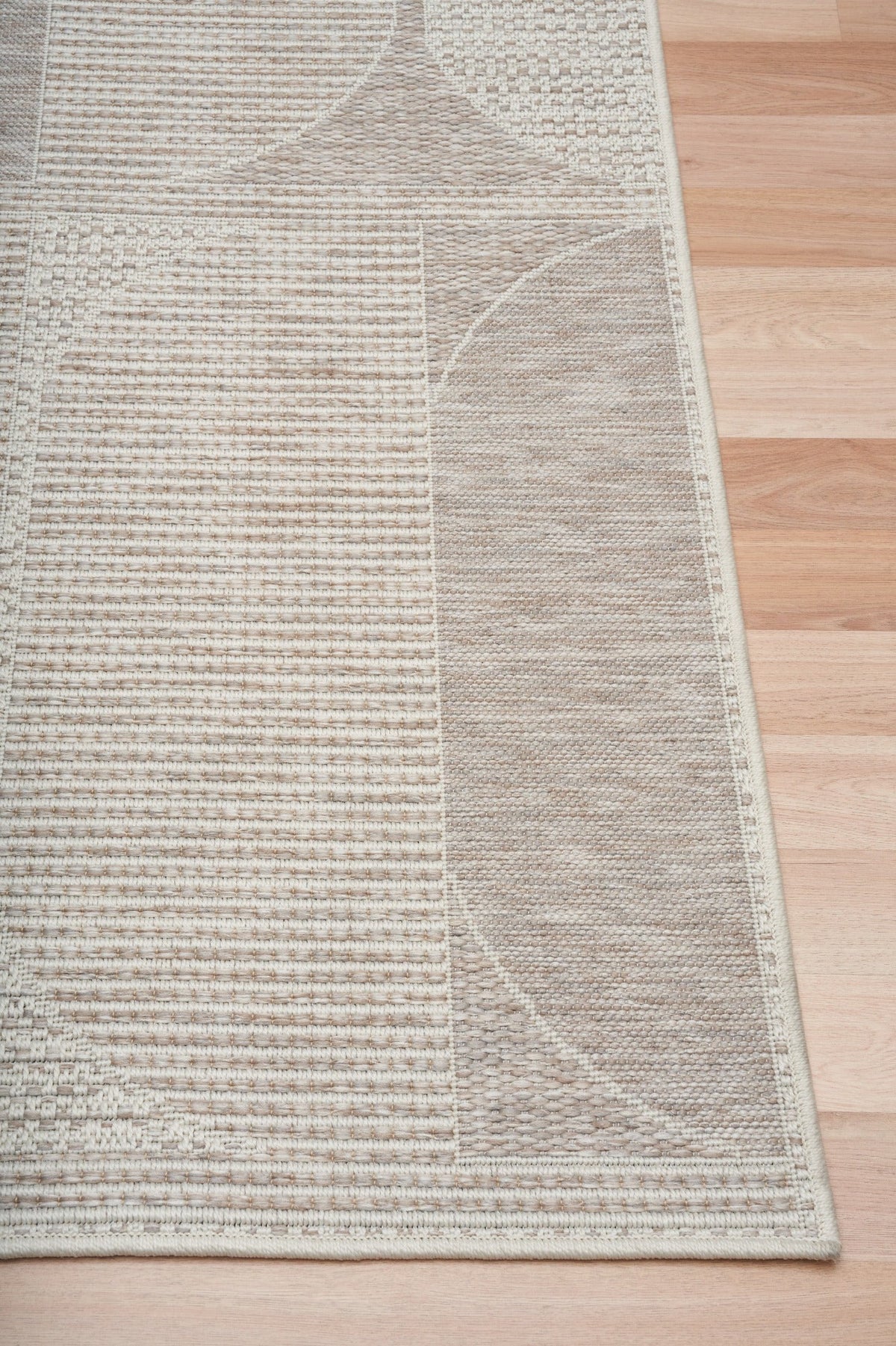Linen patio rug corner view with textured weave, beige and taupe abstract pattern