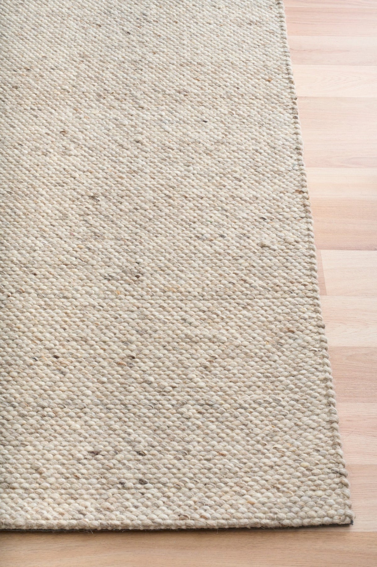 Savoy beige area rug corner with looped texture and low pile, side view