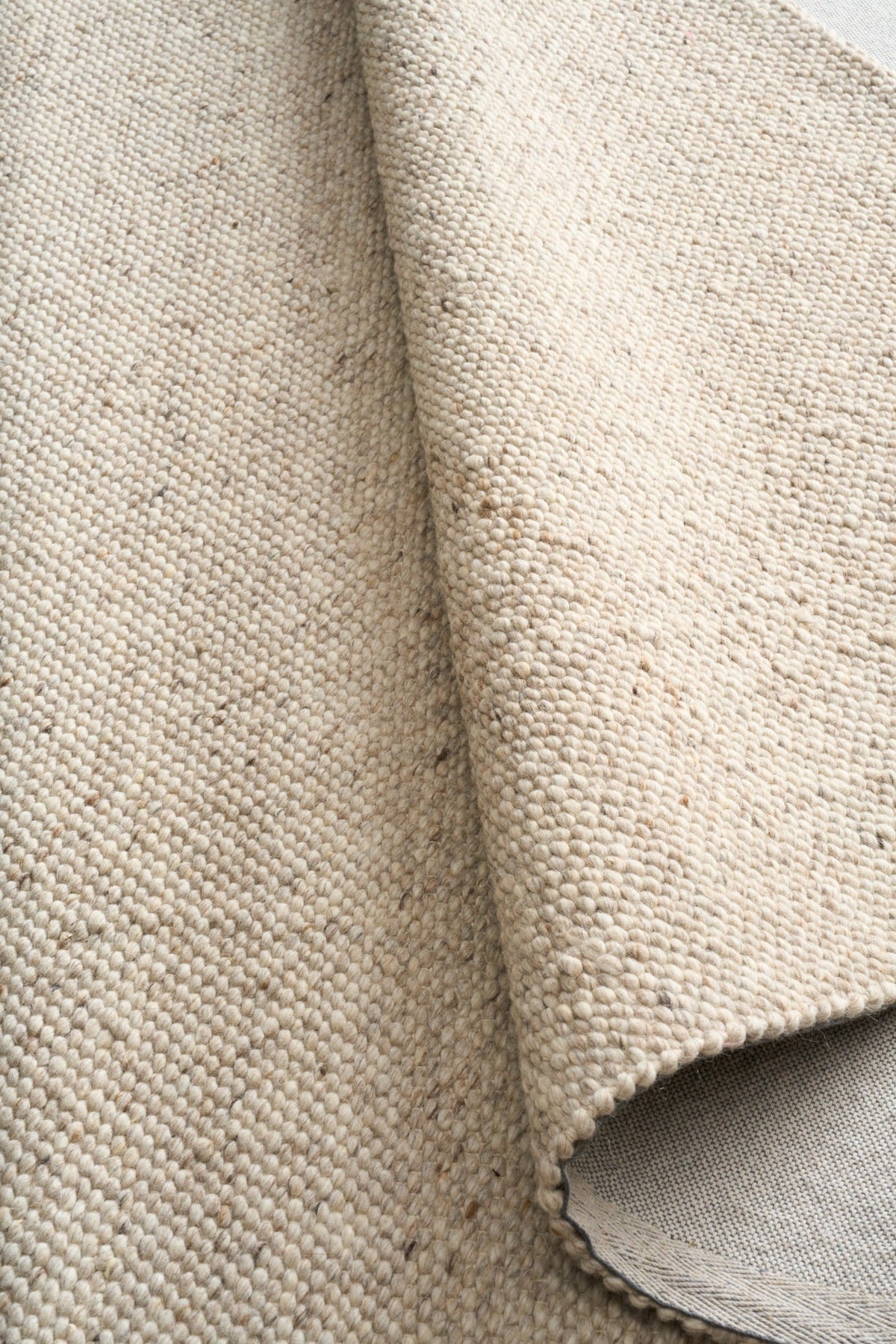Savoy beige area rug edge detail with woven border and backing