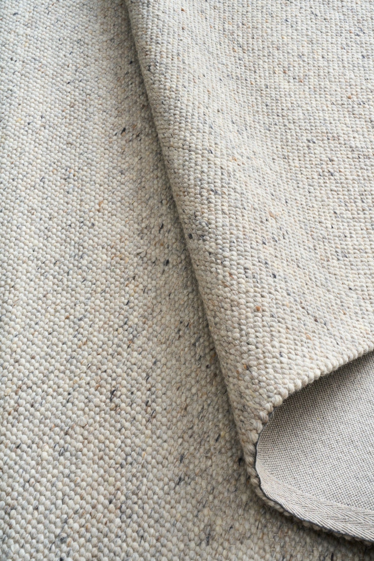 Light grey area rug close-up showing woven texture and curved rug edge