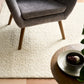 Cream sherpa rug under chair with thick curly pile texture