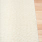 Cream sherpa rug with textured edge and dark underside backing